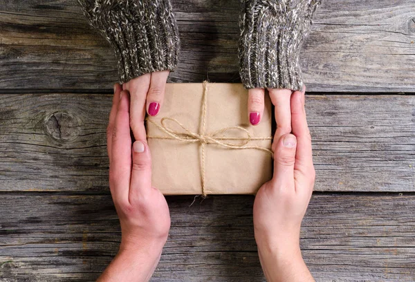 kadın el ahşap arka plan üzerinde bir Noel hediyesi veriyor adam