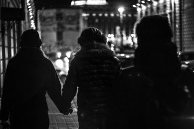 Siyah beyaz sokak fotoğrafı ön planda olan bir kişi önünde aşık çift bakar