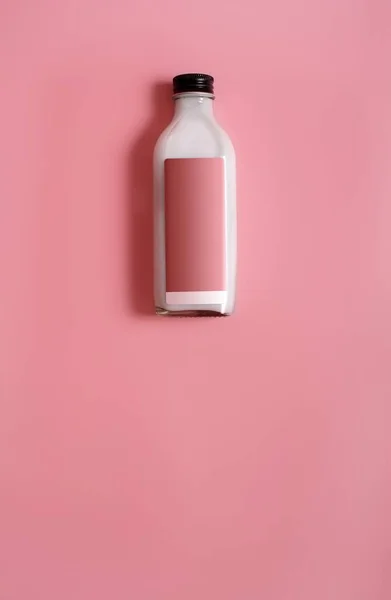 Glass bottle with white liquid (milk, cream, sauce) isolated on colour background