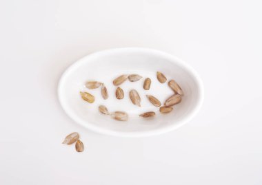 Beyaz arka planda izole edilmiş beyaz tabaklarda kurumuş ayçekirdeği.