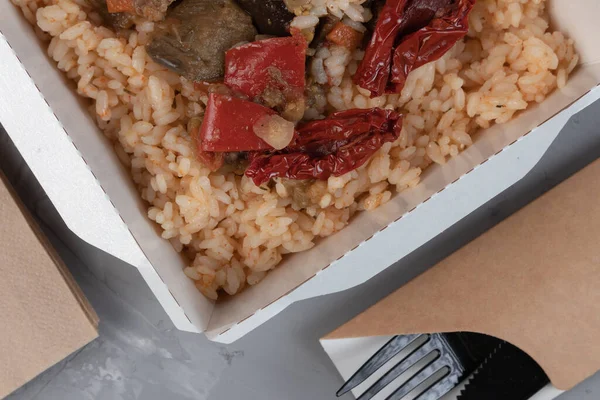 Food in eco packaging - rice with stew and vegetables, sauerkraut with carrots.