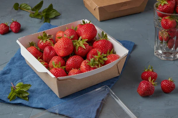 Strawberries in eco carton packaging, vegetarian food, gray background