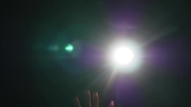 Silueta oscura de la mano masculina humana con los dedos levantados en el centro de atención o luz de fondo con gesto sobre fondo negro con rayo de brillo proyector dramático o haz — Vídeos de Stock