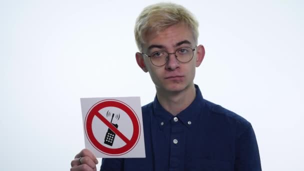 Joven sosteniendo carteles no hable por teléfono sobre un fondo blanco — Vídeo de stock