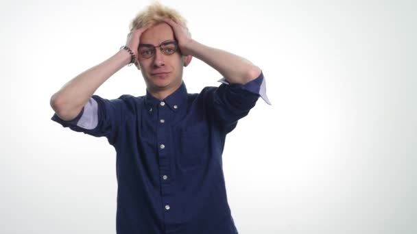 Молодой человек держит голову руками в шоке и выражает свои чувства — стоковое видео