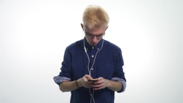 Joven hombre guapo cantando, bailando, escuchando música en auriculares sobre fondo blanco — Vídeos de Stock