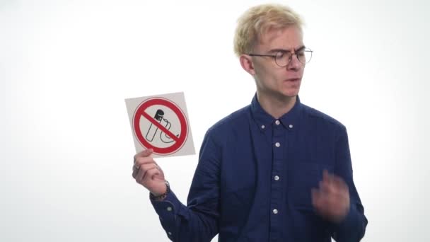 Молодий чоловік тримає ознаки, що не курить на білому тлі — стокове відео