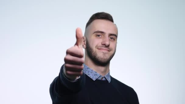 Um homem satisfeito mostra um gesto, com os polegares para cima. Fundo branco — Vídeo de Stock