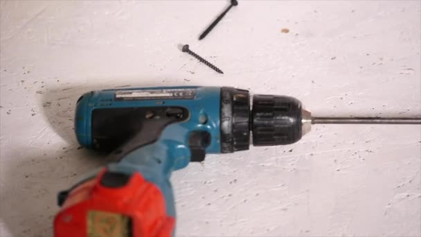 Рабочий прикрепляет доску к стене с помощью электрической отвертки — стоковое видео