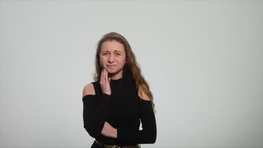 Yaralı yanağını acılı bir ifadeyle bastıran genç bir kadın korkunç bir diş ağrısı çekiyormuş gibi.