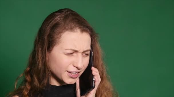 Arrabbiato giovane donna parlando sul suo cellulare su uno sfondo verde — Video Stock