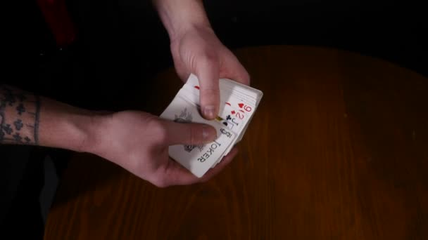 Primer plano de un mago Manos realizando trucos de cartas, haciendo que las cartas se extiendan sobre fondo negro — Vídeo de stock