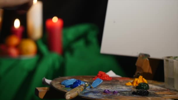 Руки художника, сжимающие краску из трубки в палитру. Крупный план — стоковое видео