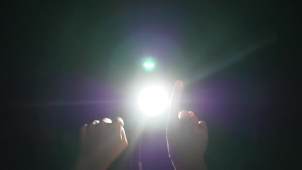 Silhouette sombre de la main masculine humaine avec les doigts levés sous les projecteurs ou la lumière du contre-jour avec un geste sur fond noir avec un rayon de rayonnement ou un faisceau de projecteur dramatique — Video