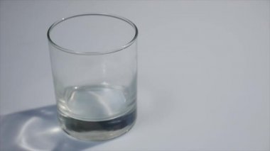 Süt cam içine dökme. Beyaz süt kadar açık cam doldurma. Beyaz arka plan önünde dökülen süt