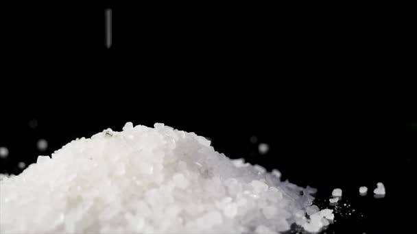 Coarse sea salt crystal falling on black background — Stock Video