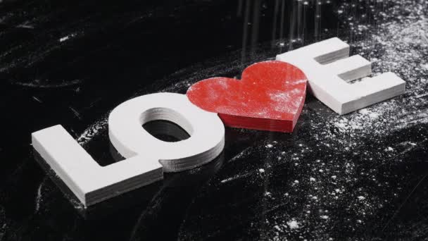 Farine est semée sur une table noire et mot amour. Préparation de la cuisson et du support. vue de dessus — Video