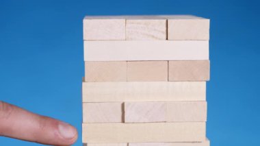 eller genç adam çalış jenga üzerinde mavi arka plan, yakın çekim