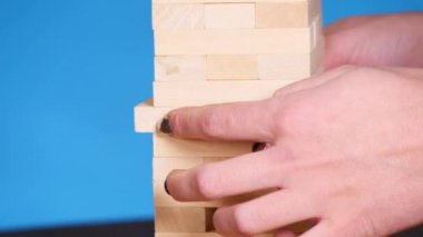 Kadının elleri boardgame Jenga oynamayı. mavi arka plan