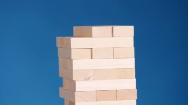 Kadının elleri boardgame Jenga oynamayı. mavi arka plan