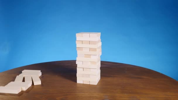 Hands of Young man plays jenga on blue background, close-up. man collapses the tower — Stock Video