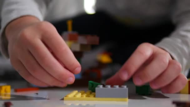 Un niño pequeño juega en el constructor. Juego de los niños diseñador. Cubos de colores. Los brazos pequeños son cubos conectados entre sí — Vídeos de Stock