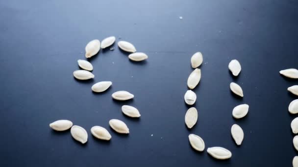 Pumpkin seeds on the dark background. word SUN of Pumpkin seeds — Stock Video