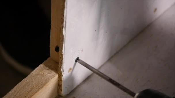 Arbetaren fixar styrelsen på väggen med elektrisk skruvmejsel — Stockvideo
