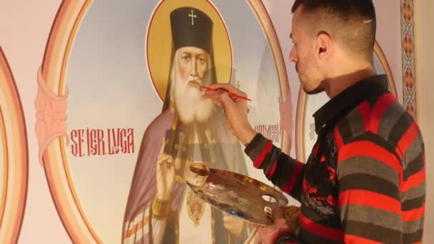 30.01.2018, Chernivtsi, Ucrânia - Artista Masculino está de pé e pintando o Ícone do Santo Ortodoxo, segurando uma paleta com tintas — Vídeo de Stock