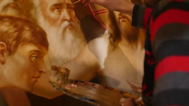 30.01.2018, Chernivtsi, Ucrania - Artista masculino está de pie y pintando el icono del santo ortodoxo, sosteniendo una paleta con pinturas — Vídeo de stock