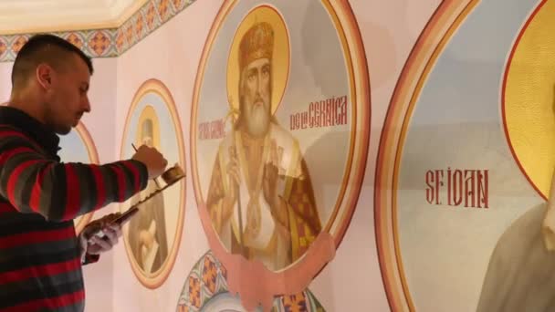 30.01.2018, Tsjernivtsi, Oekraïne - mannelijke artiest is permanent en schilderen de pictogram van orthodoxe heilige, die houden van een palet met verven — Stockvideo