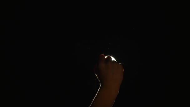 Silueta oscura de la mano masculina humana con los dedos levantados en el centro de atención o luz de fondo con gesto sobre fondo negro con rayo de brillo proyector dramático o haz — Vídeos de Stock