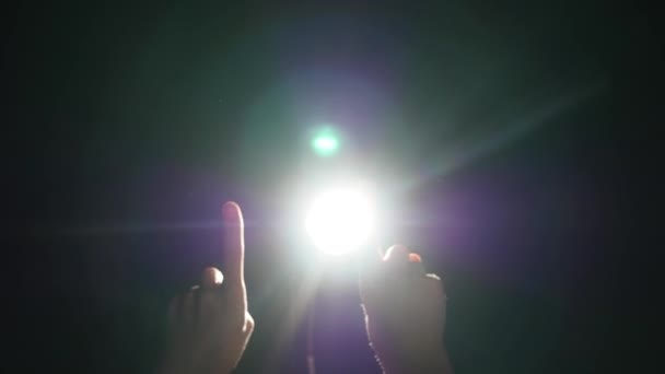 Dark silhouette of human male hand with raised fingers in spotlight or backlight light with gesture on black background with dramatic projector shine ray or beam — Stock Video