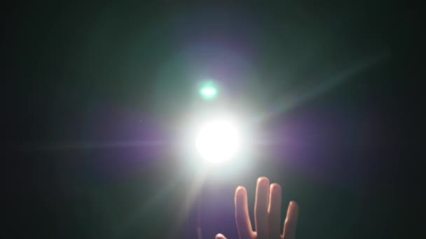 Silueta oscura de la mano masculina humana con los dedos levantados en el centro de atención o luz de fondo con gesto sobre fondo negro con rayo de brillo proyector dramático o haz — Vídeo de stock