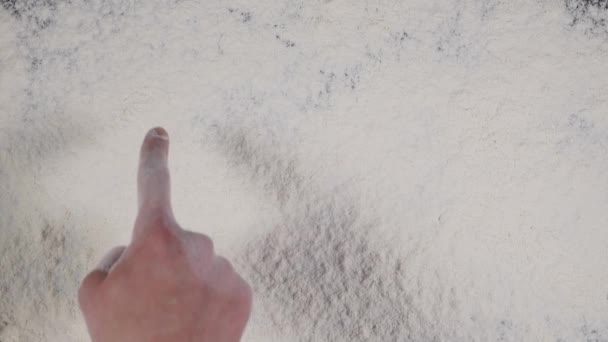 Écrivez un doigt SMILE sur un fond de farine blanche. vue du dessus 4k — Video