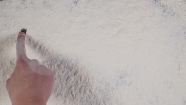 Escreva um dedo BREAD em um fundo de farinha branca. vista superior 4k — Vídeo de Stock