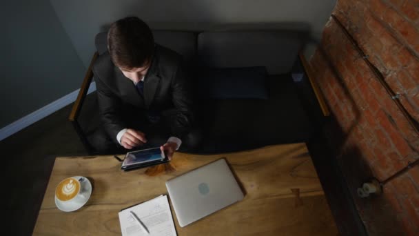 Бизнесмен использует планшетный компьютер в кафе на деревянном столе. вид сверху — стоковое видео