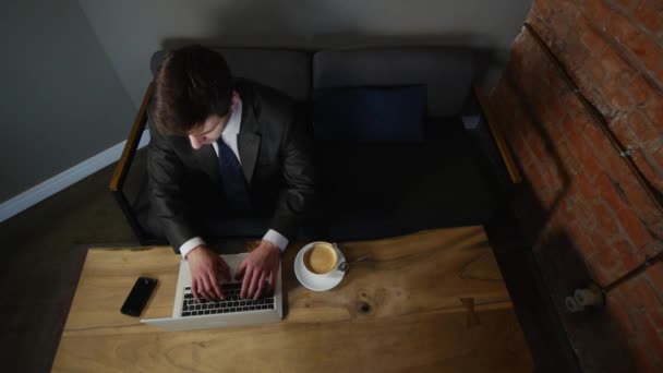 Бизнесмен работает на ноутбуке и пьет кофе в кафе. вид сверху — стоковое видео