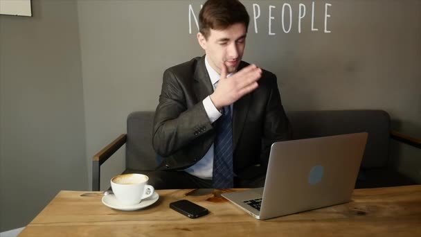 Hombre de negocios guapo getiing cansado de trabajar en el ordenador portátil en la cafetería — Vídeo de stock