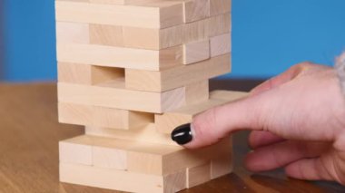 Kadının elleri boardgame Jenga oynamayı. mavi arka plan