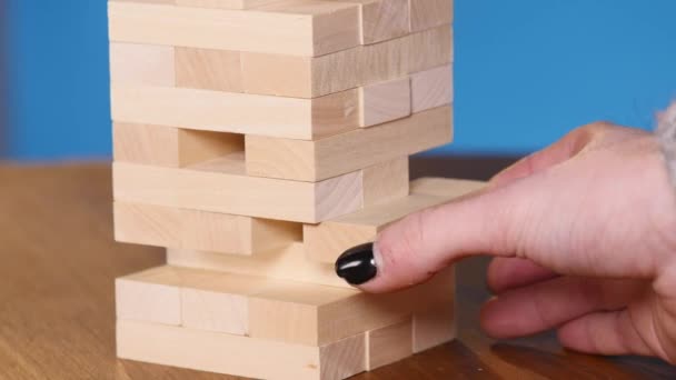 Dames handen spelen boardgame Jenga. blauwe achtergrond — Stockvideo