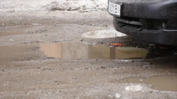 Slowmotion, Close Up: Modderig water spatten over asfaltweg als de auto rijdt in plas. Bruine vloeistof spuit over zwart straat — Stockvideo