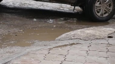 Ağır çekim, Close Up: Bulanık su su birikintisi içine araba sürücüleri olarak asfalt yol boyunca su sıçramalarına. Siyah sokak boyunca kahverengi sıvı spreyler