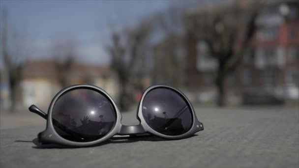Okulary przeciwsłoneczne leżą na drodze. podnieść ręce damskie Sunglases — Wideo stockowe