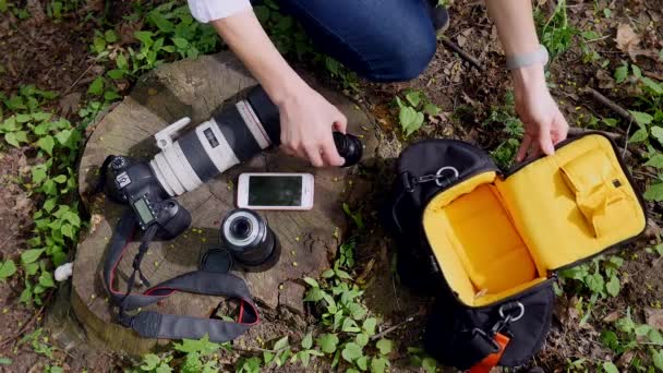 A câmara e o telefone estão na relva. Fotógrafo reúne tudo no saco — Vídeo de Stock