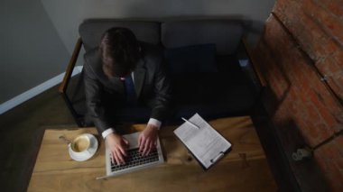 Kafede otururken dizüstü bilgisayar üzerinde çalışan genç bir adam onun laptop kapatır ve alonng gitmek.