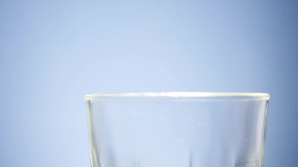 Milch ins Glas gießen. weiße Milch füllt klares Glas auf. Milch ergießt sich vor weißem Hintergrund — Stockvideo