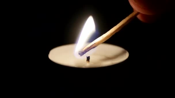 Gros plan d'une allumette allumant une bougie sur un fond noir 