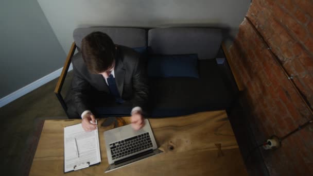 Бизнесмен использует ноутбук в кафе и держит биткойн в руке на деревянном столе. вид сверху — стоковое видео