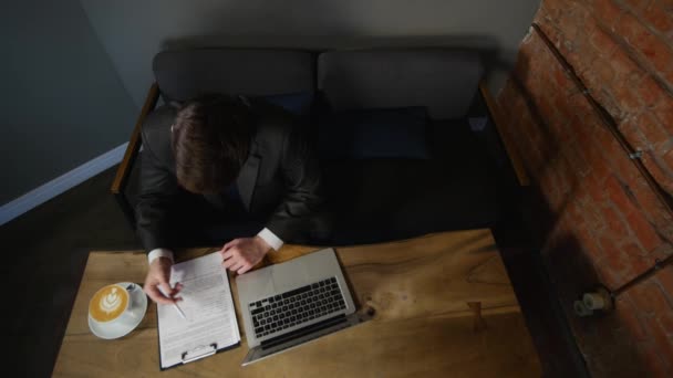 De zakenman ondertekent de documenten in het café. bovenaanzicht — Stockvideo